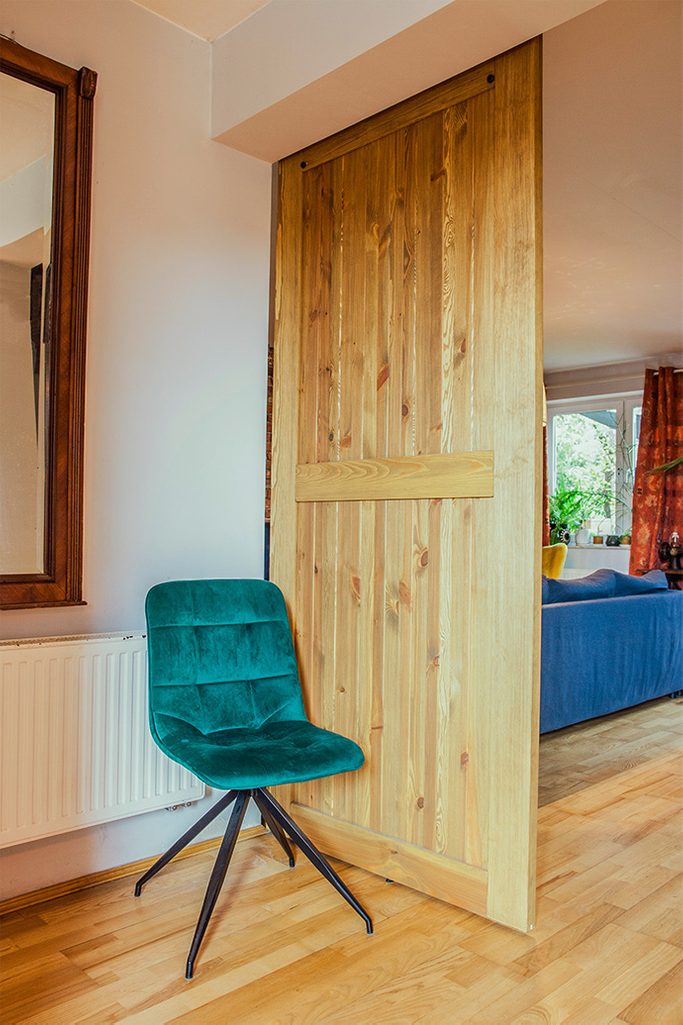 rustikale Holztür, Schiebetür aus gebürstetem Holz, barn door, grüner Veloursstuhl