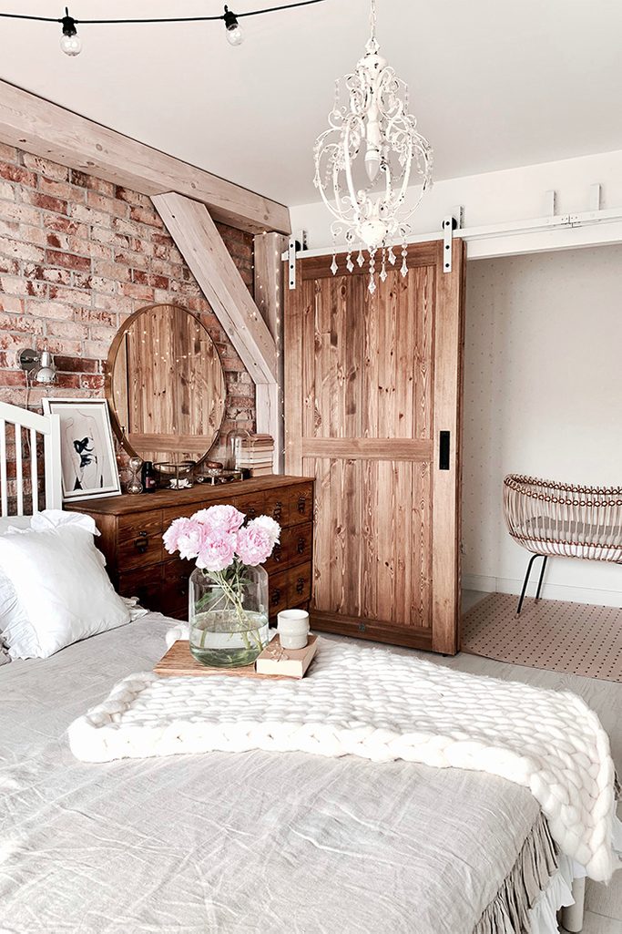 Rustikal Schlafzimmer, Holzschiebetüren, Bypass Schiebetüren, Bypass Wandhalterung für Schiebetüren, rustikaler Stil im Innenraum, moderner rustikaler Stil, Scheunen-Schiebetüren, weiße Schiebesystem, Backsteinmauer im Schlafzimmer, Deckenbalken im Schlafzimmer, weiße rustikale Kronleuchter