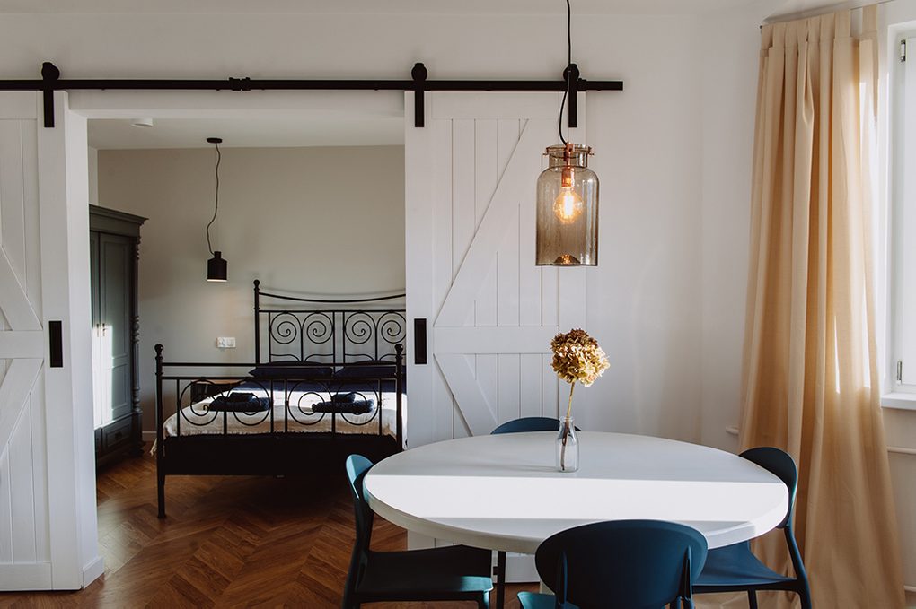 moderner Retro-Stil, Mietwohnungen Wroclaw, Doppelschiebetüren, weiße Schiebetüren, barn door, offener Raum, Doppeltür zu Schlafzimmer, Retroschlafzimmer, rustikale Pendelleuchte, Metallbett