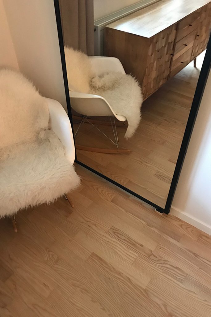 Schiebetür mit Spiegel, Tür mit Spiegel in einem Metallrahmen, Schiebetür in einem modernen Interieur, moderne Kommode im Retro-Stil, weißer Schaukelstuhl, Spiegel im Wohnzimmer