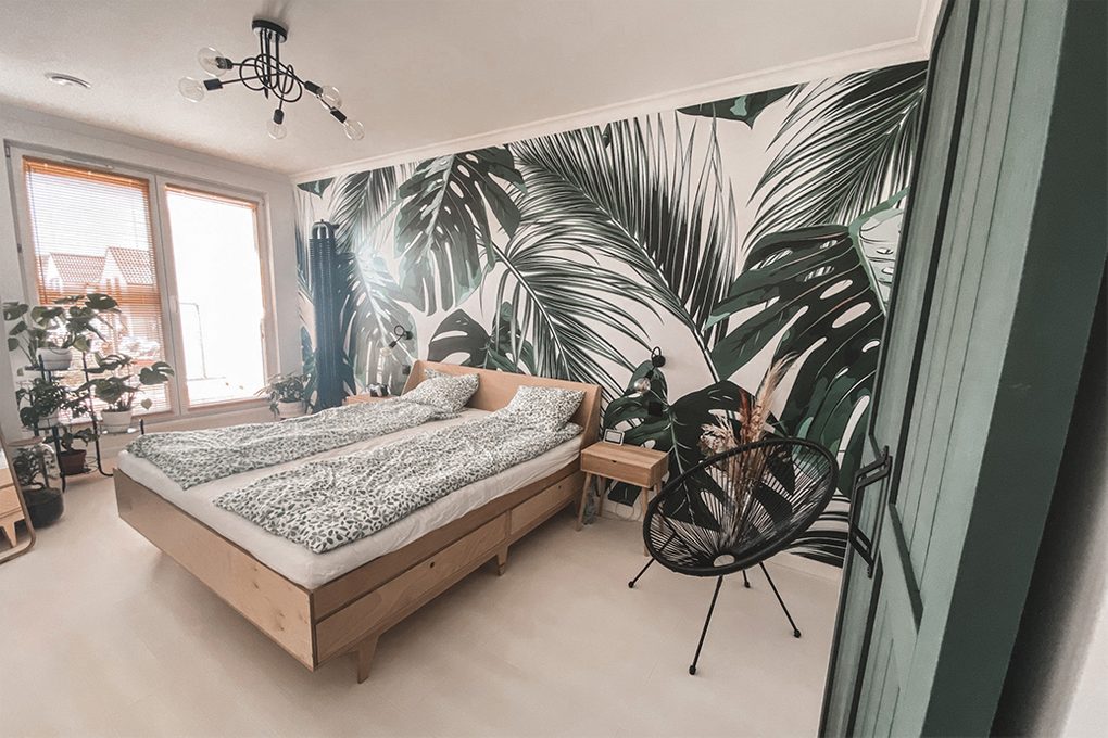 grüne Türen, helles Holz im Schlafzimmer, helles Holz und Grün, Grün im Schlafzimmer, Pflanzenmotiv im Schlafzimmer, botanische Tapete, dekorative Tapete im Schlafzimmer, Leinen mit Blumenmotiv, Pflanze im Schlafzimmer, industrieller Kronleuchter im Schlafzimmer , schwarzer durchbrochener Sessel, helles Holzbett, kleine Nachttisch aus hellem Holz