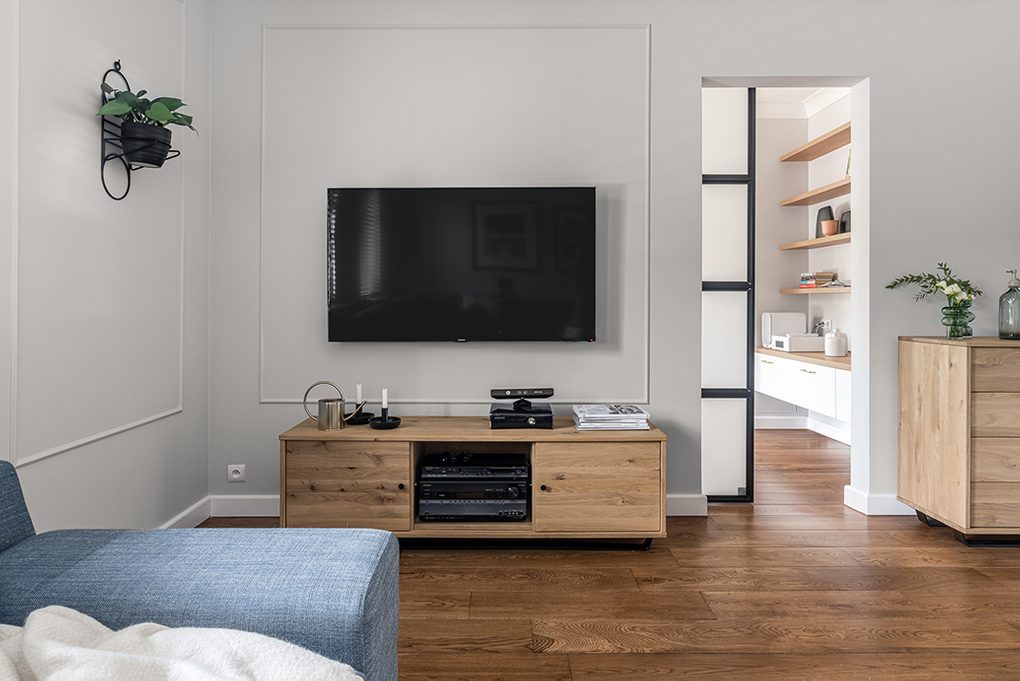 TV-Ecke im Wohnzimmer, TV-Schrank aus hellem Holz, blaues Denim Sofa, Eingang zum großen Wohnzimmer mit Schiebetüren, Holzboden im Wohnzimmer, helle Holzmöbel