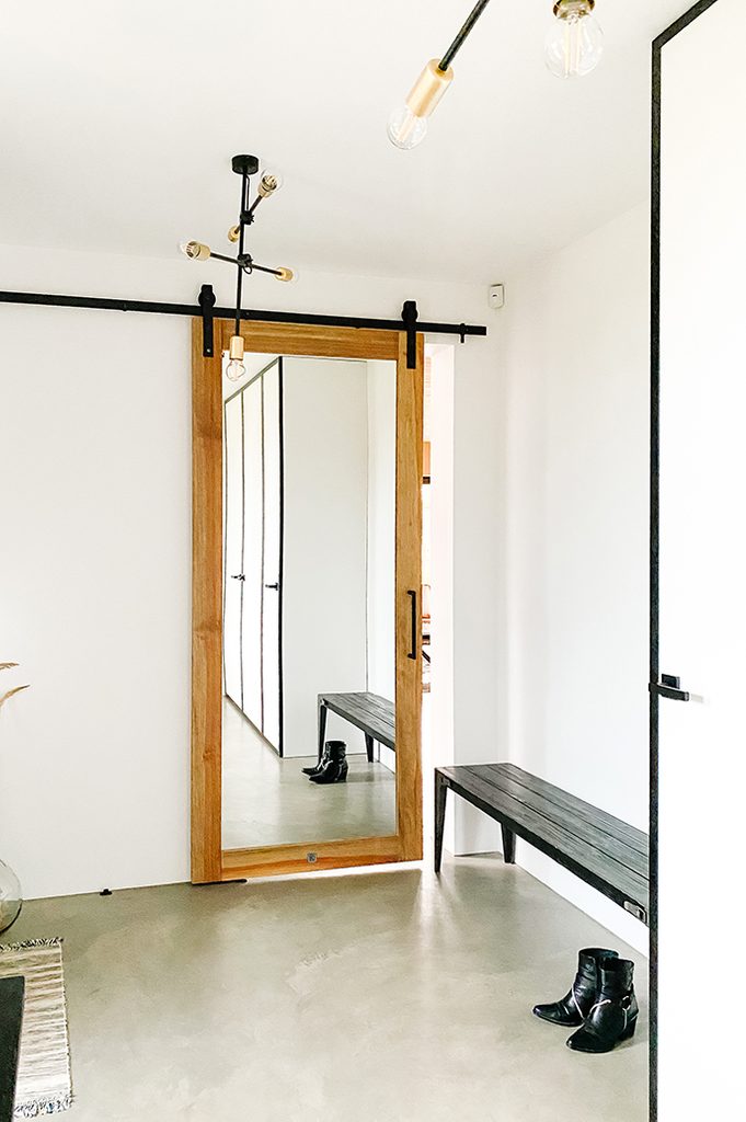 Spiegeltür im Vorraum, schwarze Bank im Foyer, weißer und schwarzer minimalistischer Vorraum, Mikrozement Boden