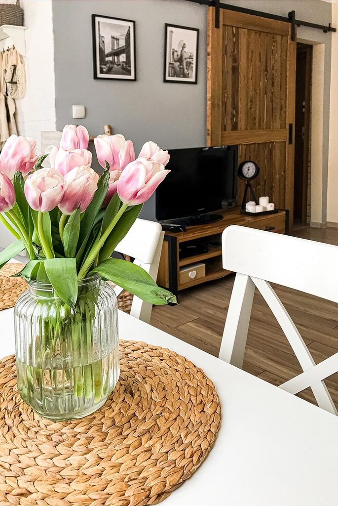 Schiebetüren in einer kleinen Wohnung, Tulpen auf weißem Esstisch in kleinem Wohnzimmer, Schiebetür in kleiner Wohnung, weißer Esstisch und Stühle