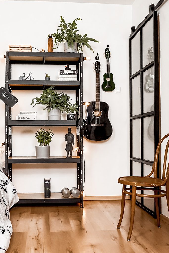 studentenzimmer einrichten, Bücherregal im Loft-Stil, Pflanzen auf Metallregal, Schiebetür aus Metall und Glas, Vintage-Stuhl, an der Wand hängende Gitarren