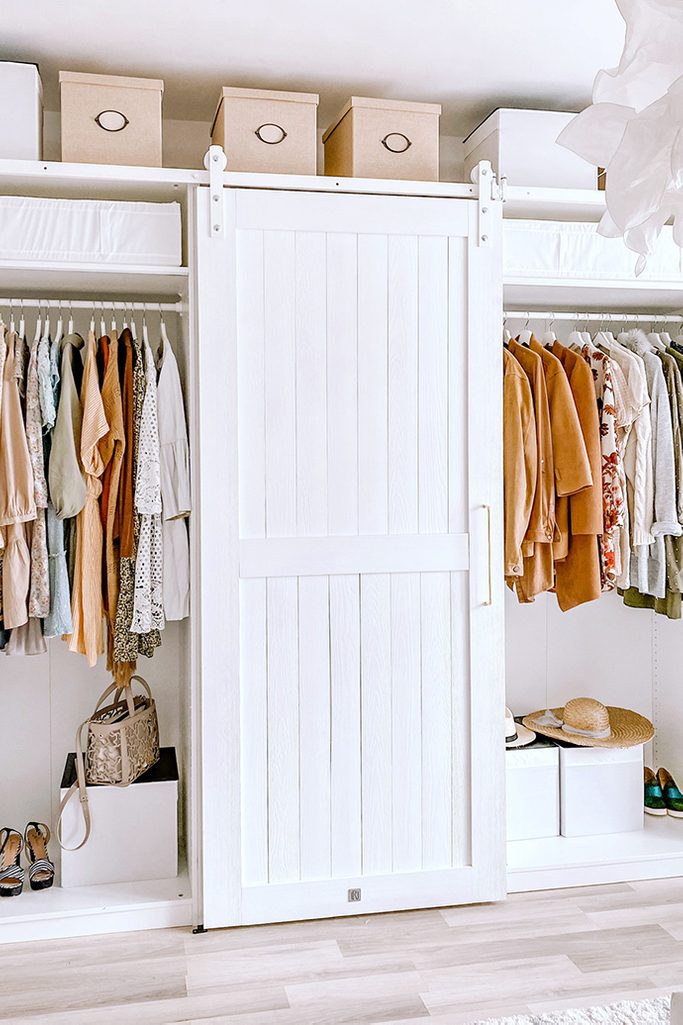 weiße Holztüren auf weißem Schiebesystem, weiße Kleiderschränke, begehbarer Kleiderschrank