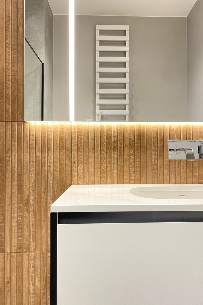 Modernes Badezimmer mit weißen Armaturen und holzfarbenen Fliesen