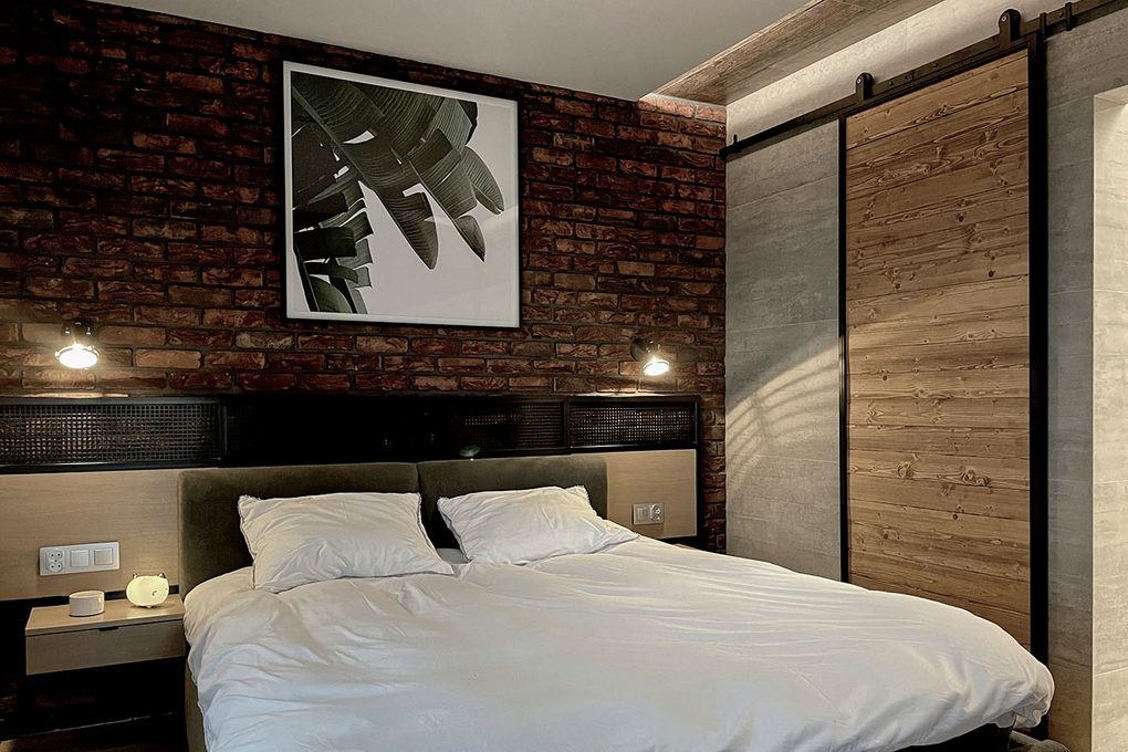 Schlafzimmer industrial, roter backstein an der wand im schlafzimmer, schwarz-weißes plakat über dem bett, industrielle schiebetür für das badezimmer