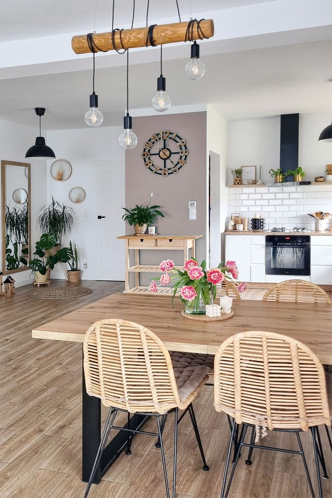 Durchbrochene Stühle an einem Tisch mit Holzplatte in einem offenen Esszimmer kombiniert mit einer Küche im skandinavischen Stil