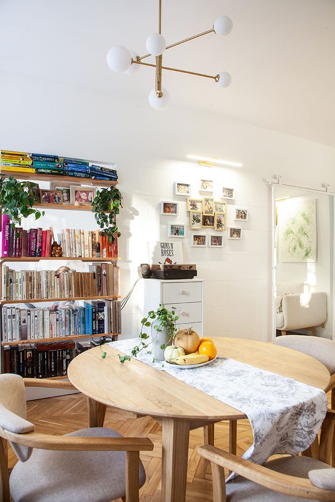 Ein runder Holztisch und ein Bücherregal mit Büchern im Inneren einer kleinen Wohnung