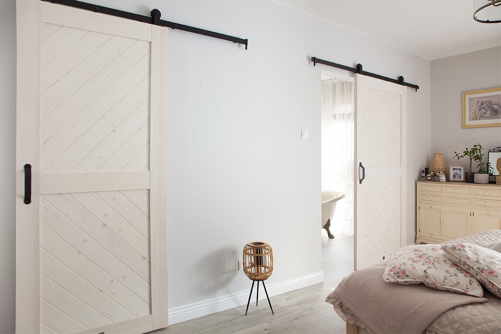 weiße Schiebetür zum Badezimmer in einem im provenzalischen Stil eingerichteten Schlafzimmer