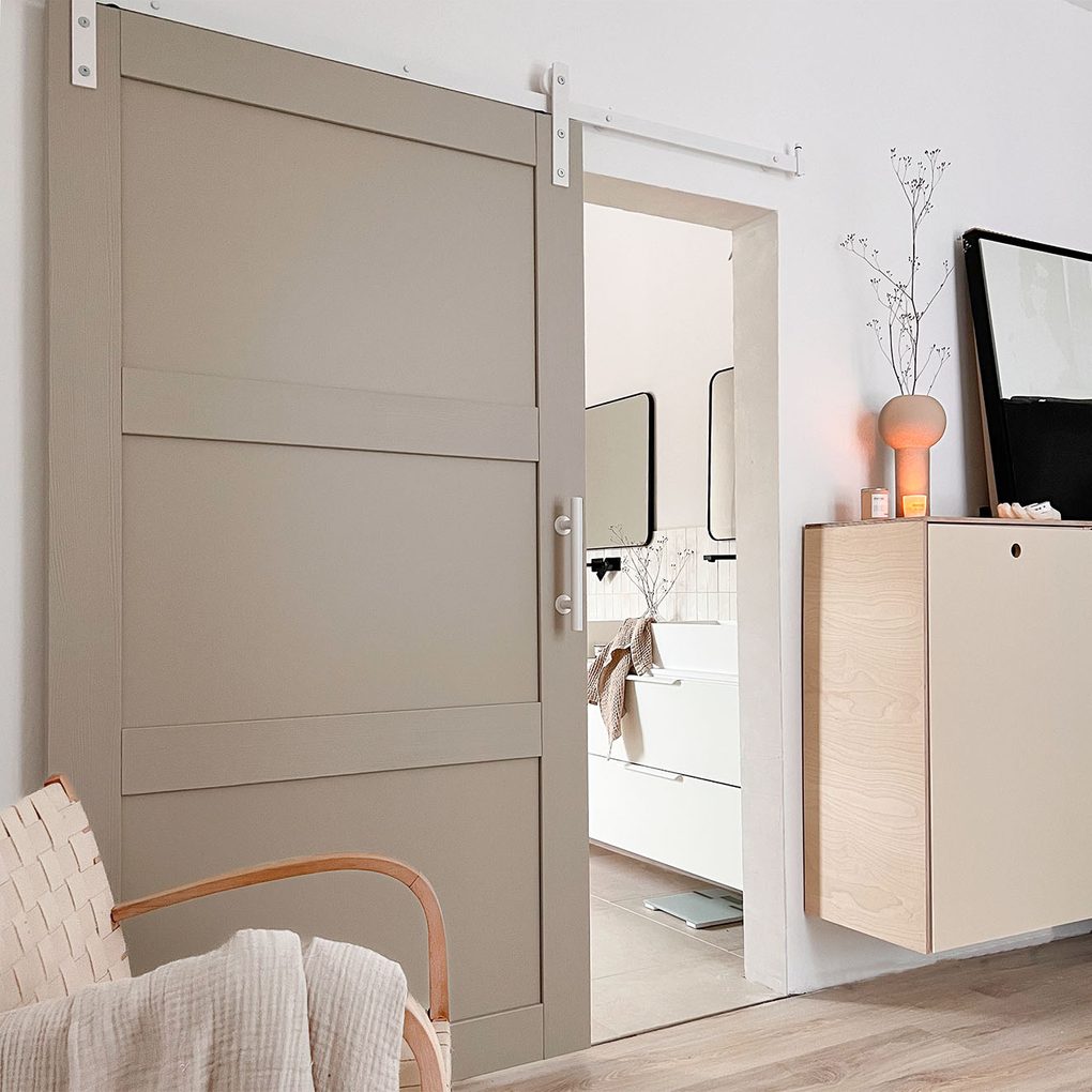 kieselgraue Tür an einem weißen Schiebesystem im Eingang zum Badezimmer