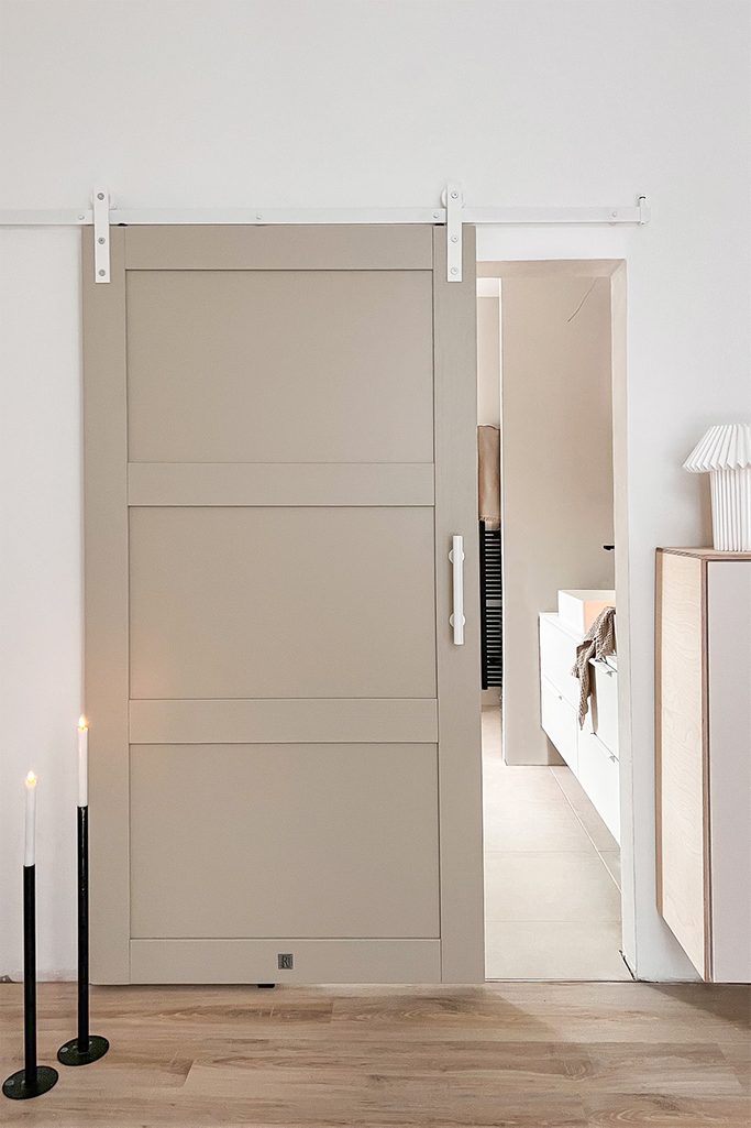 offene kieselgraue Schiebetür mit einem weißen Schiebesystem, das ein Fragment des Badezimmers zeigt