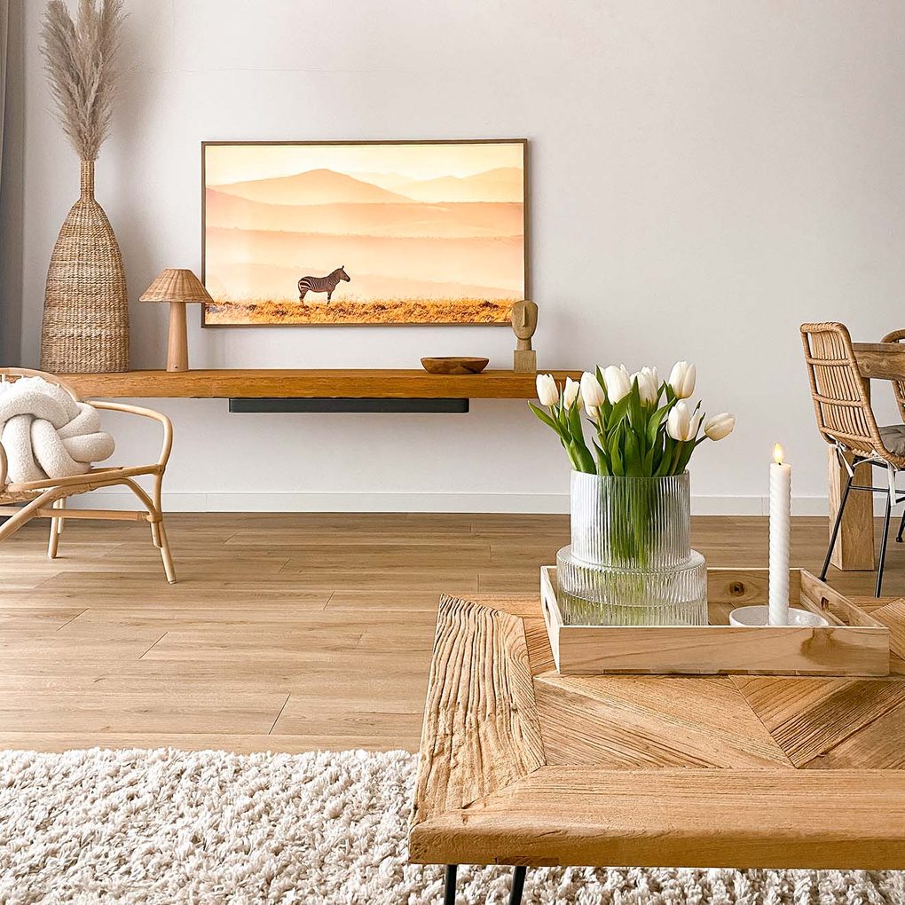 Weiße Wände, Holzpaneele, ein hölzerner Couchtisch und gewebte Seegrasdekorationen im Wohnzimmer