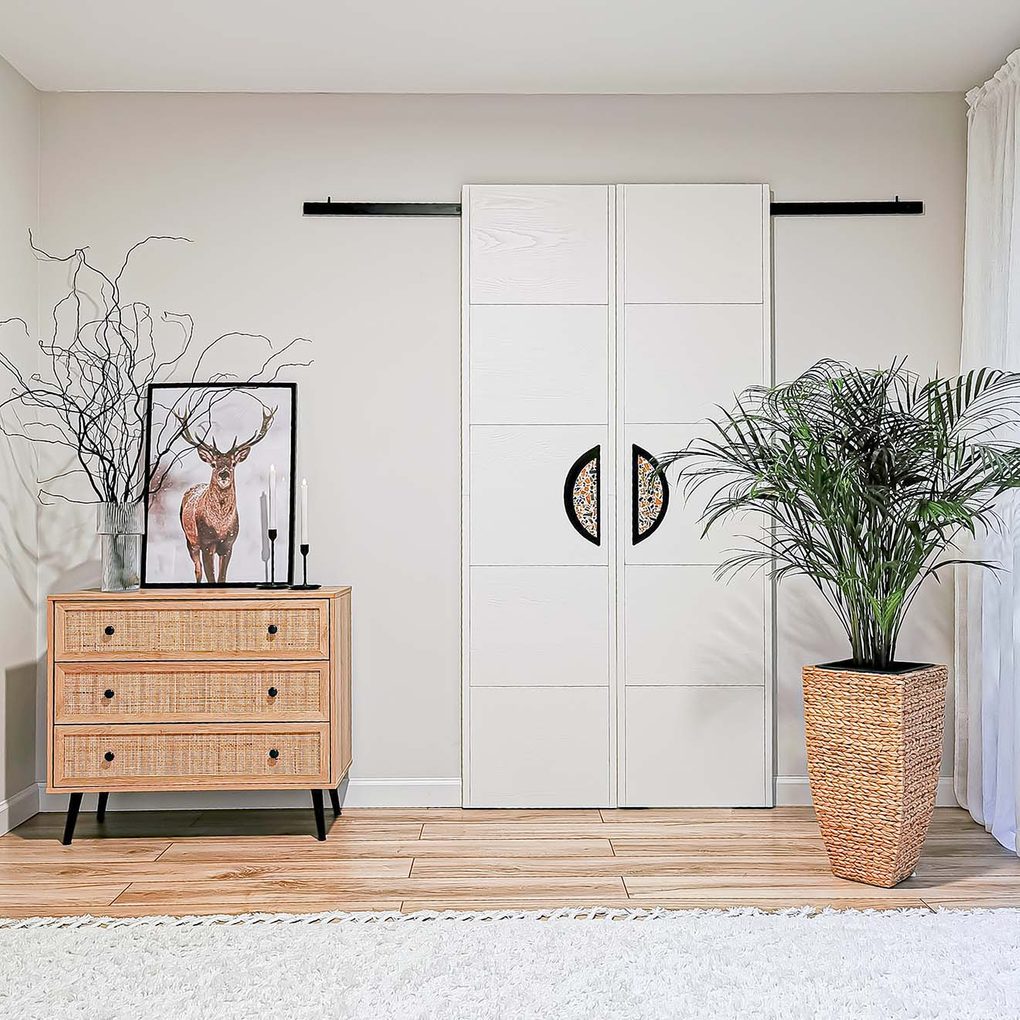 eine Kommode mit Schubladenfronten aus Rattan, die neben zwei weißen Schiebetüren im minimalistischen Stil steht